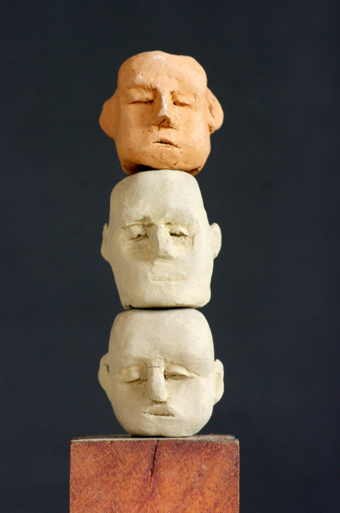 Totem . Trois têtes en terre cuite sur socle bois de Philippe Doberset
