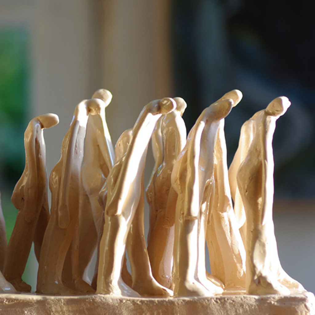 Groupe de personnages en marche. Terre blanche. Sculpture de Philippe Doberset