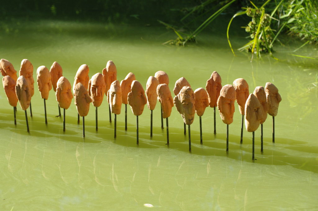 Les passants de l'ile. Série de têtes sur plan d'eau Installation de Philippe Doberset