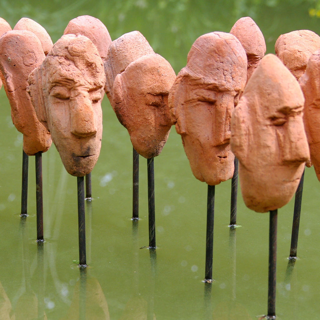 Les passants de l'ile. Série de têtes en terre cuite sur plan d'eau Installation de Philippe Doberset