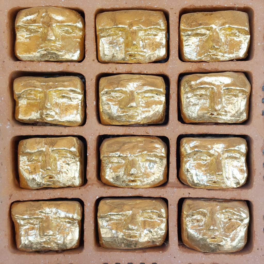 Série de visages dorés à l'or fin inclus dans de la brique industrielle. Sculpture de Philippe Doberset