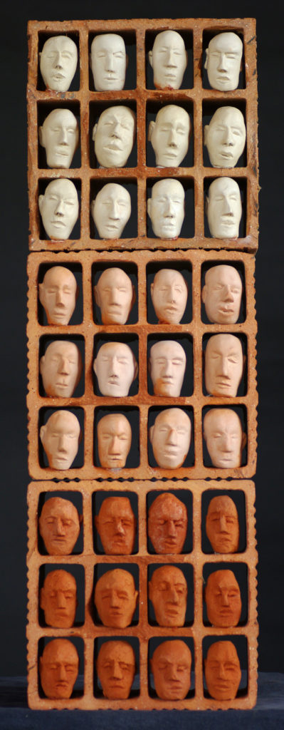 Groupe de personnages en terre cuite installés dans des modules en brique découpées. Sculpture de Philippe Doberset