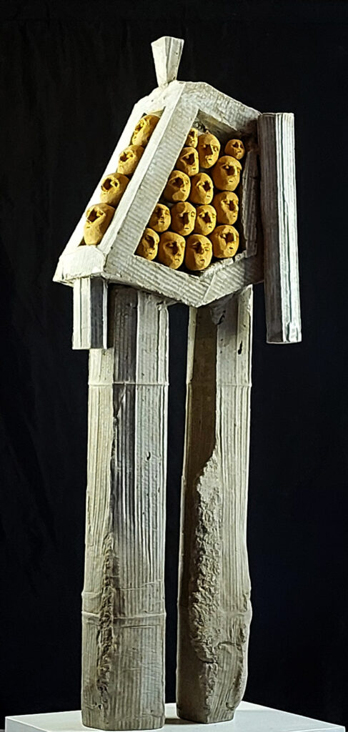 Sculpture de Philippe Doberset représentant un personnage en béton enfermant une série de petits personnages en terre cuite