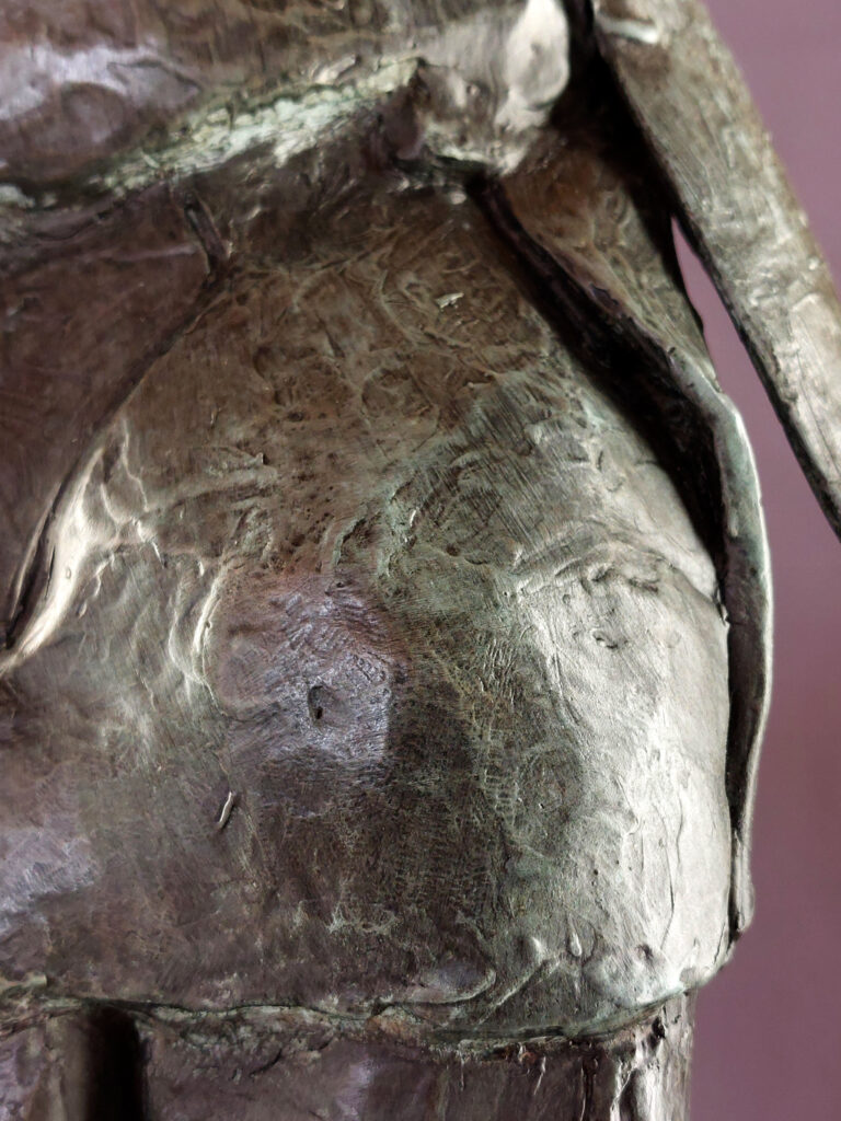 Sculpture en bronze de Philippe Doberset représentant un grand personnage  les bras ballants dans une pose déhanchée. Vue d'un détail